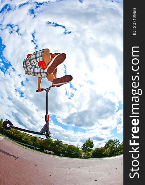 Boy jumping with his scooter in the skate park