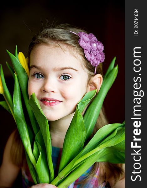 Portrait of a sunny child girl with tulips on a dark background. Portrait of a sunny child girl with tulips on a dark background