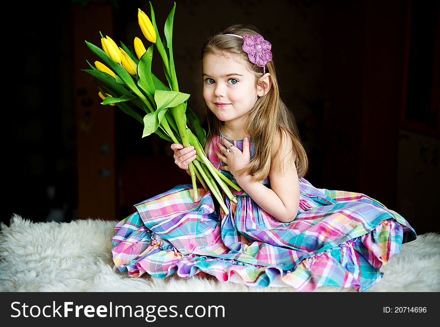 Portrait of a sunny child girl with tulips on a dark background. Portrait of a sunny child girl with tulips on a dark background