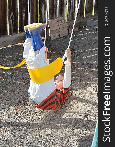 Young blond boy playing outdoors on swing set. Young blond boy playing outdoors on swing set