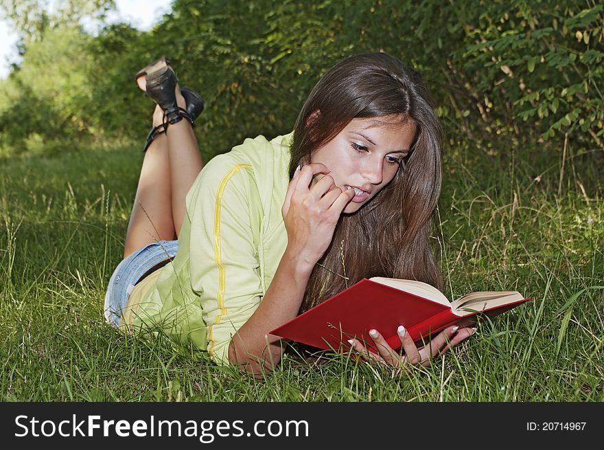 Beautiful girl reading a book while lying in the grass. Beautiful girl reading a book while lying in the grass