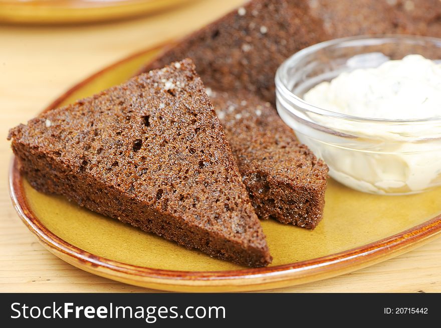 Black bread toasts with garlic sauce on a plate