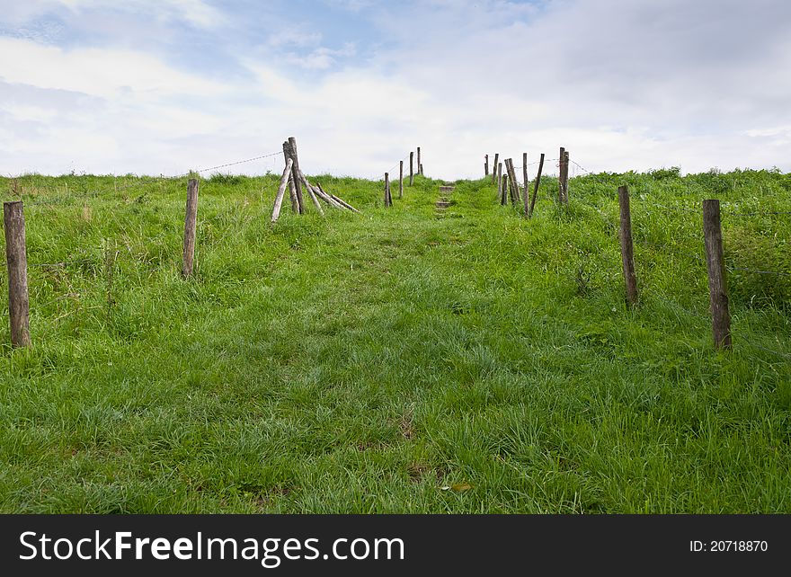Path upwards between fences with barbed wire