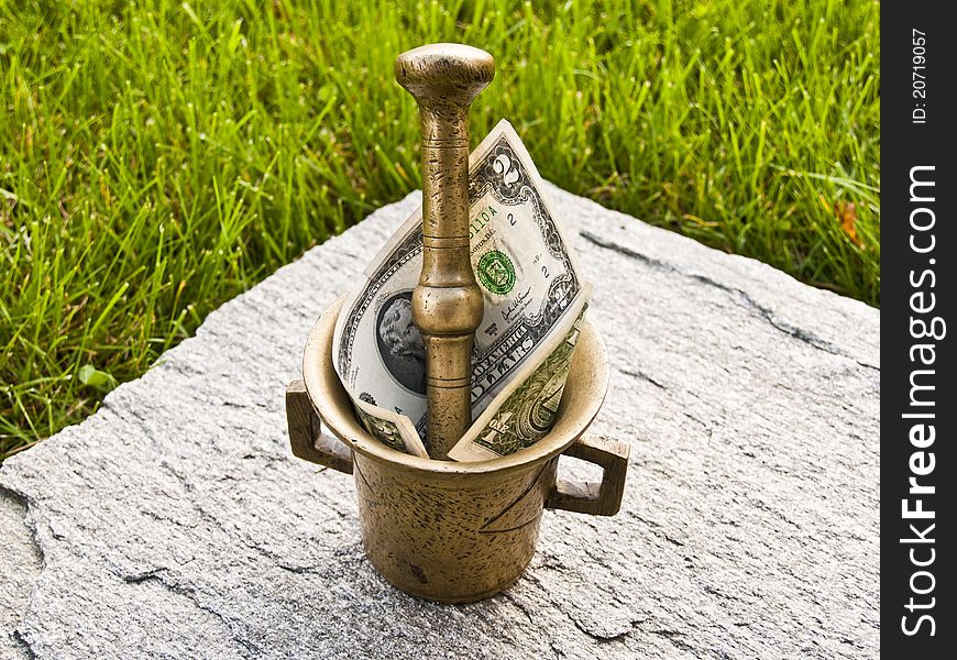 Mortar grinds dollars, loans and credit cards. Brass mortar with dollars. Mortar grinds dollars, loans and credit cards. Brass mortar with dollars.