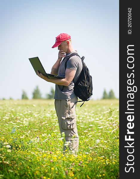 Young man working with laptop on blue sky background