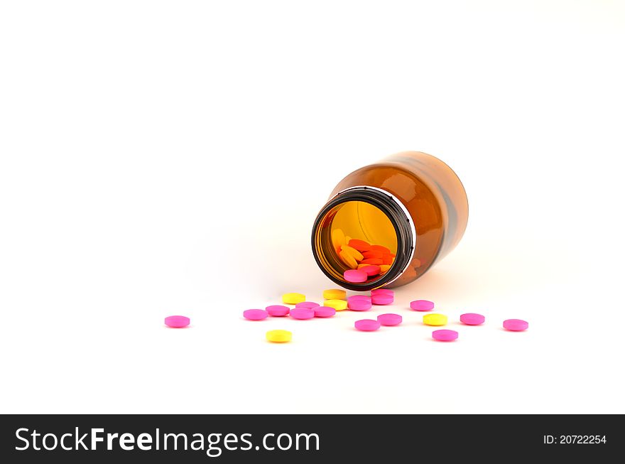 Yellow and pink pills spilling out of bottle (protect from ligh) isolated on white background. Yellow and pink pills spilling out of bottle (protect from ligh) isolated on white background