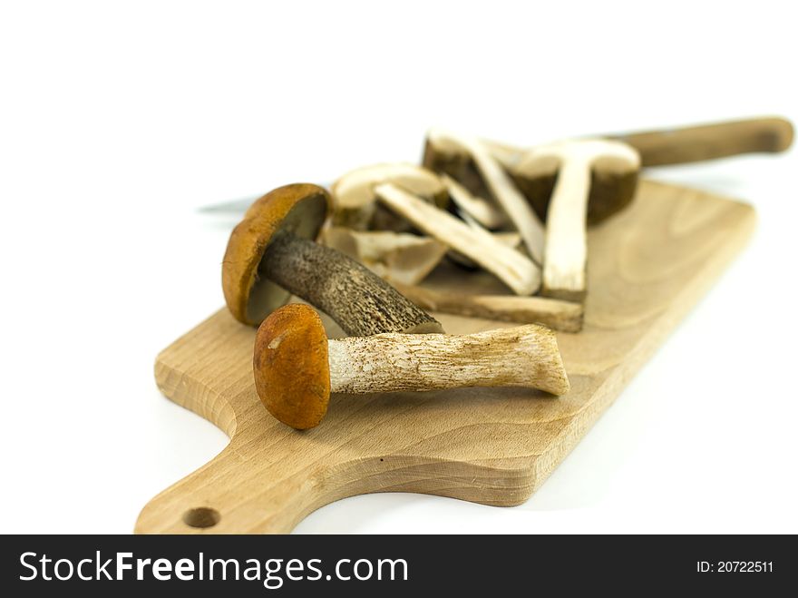 Wild edible mushrooms on a cutting board on white background