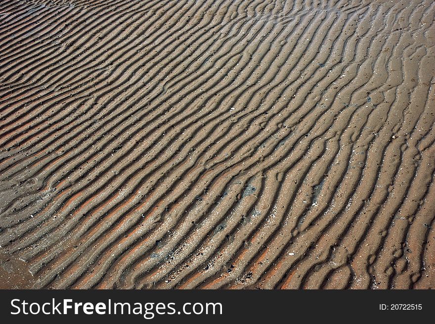 Patterns of sand on the seashore are receding