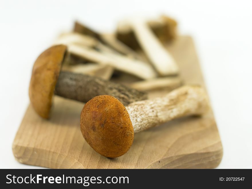 Wild edible mushrooms on a cutting board on white background