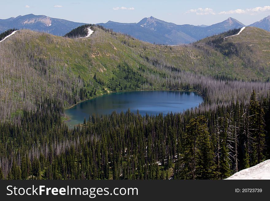 This image of the mountain lake (Clayton Lake), surrounded by forest and mountains with snow cornices was taken in NW Montana.