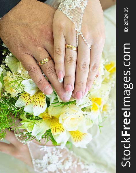 Hands of bride and groom with wedding rings over the bridal bouquet. Hands of bride and groom with wedding rings over the bridal bouquet