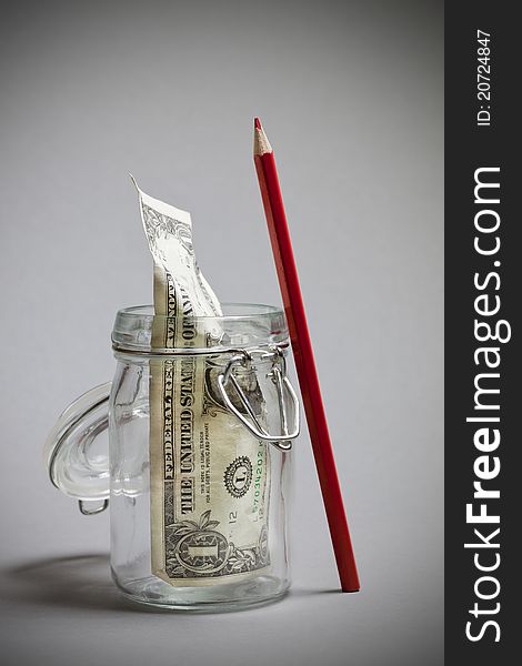 Dollar note in a jar with red pencil concept. Dollar note in a jar with red pencil concept