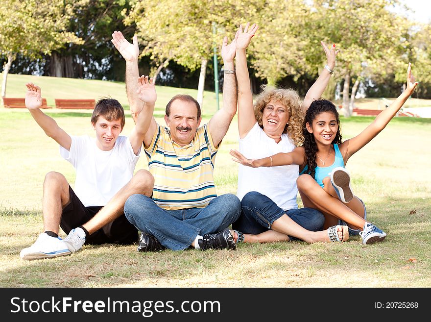 Family with raised hands enjoying in park. Family with raised hands enjoying in park.