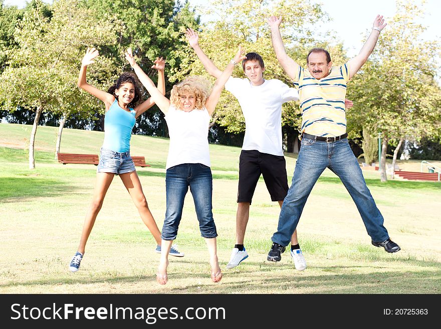 Family Jumping High In The Air On A Green Meadow