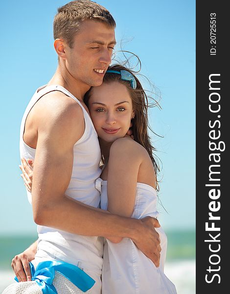 Portrait of young man and woman embracing as a happy romantic couple on a beach. Couple enjoying a summer vacation.