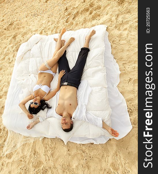 Beautiful young couple resting in bed in morning on the beach