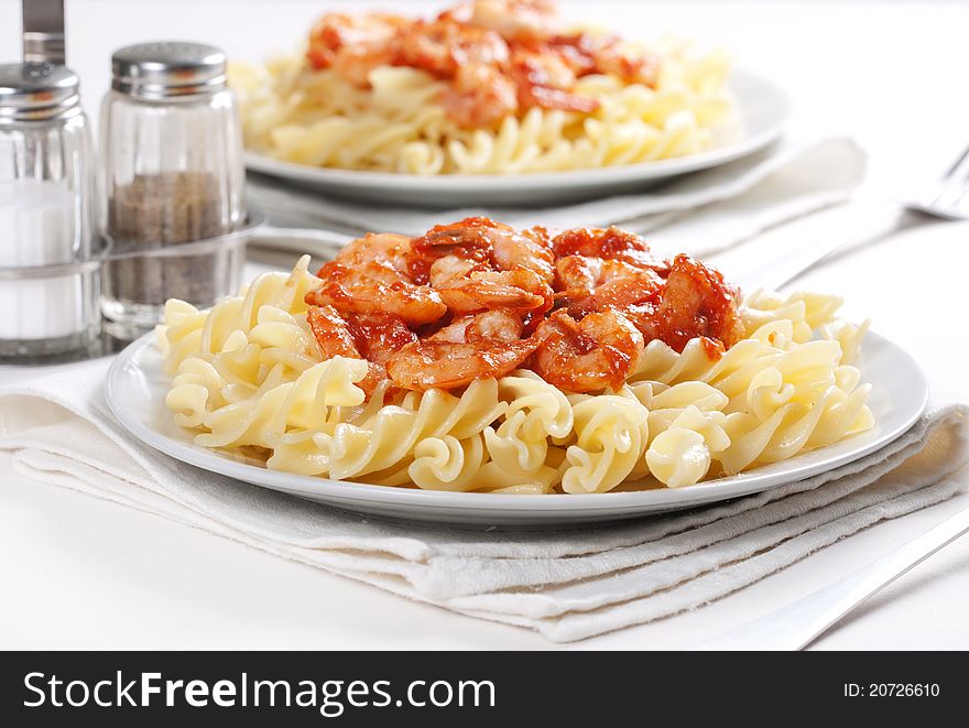 Two plates of pasta with tomato and shrimps