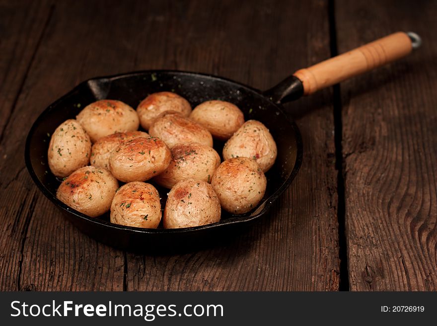 Roasted potatoes with sea salt and herbs in pan on rustic table