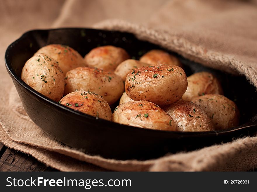 Roasted potatoes with sea salt and herbs in pan on rustic table