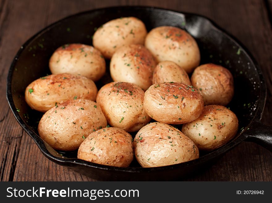 Roasted potatoes with sea salt and herbs in pan on rustic table