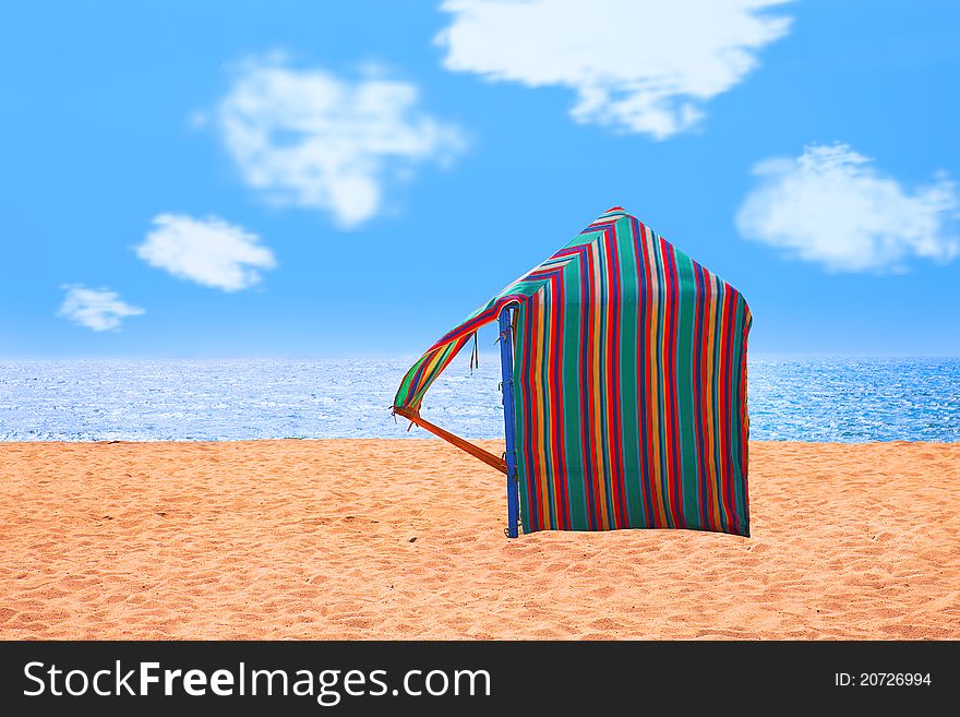 Colored hut on a deserted beach with the sea as background