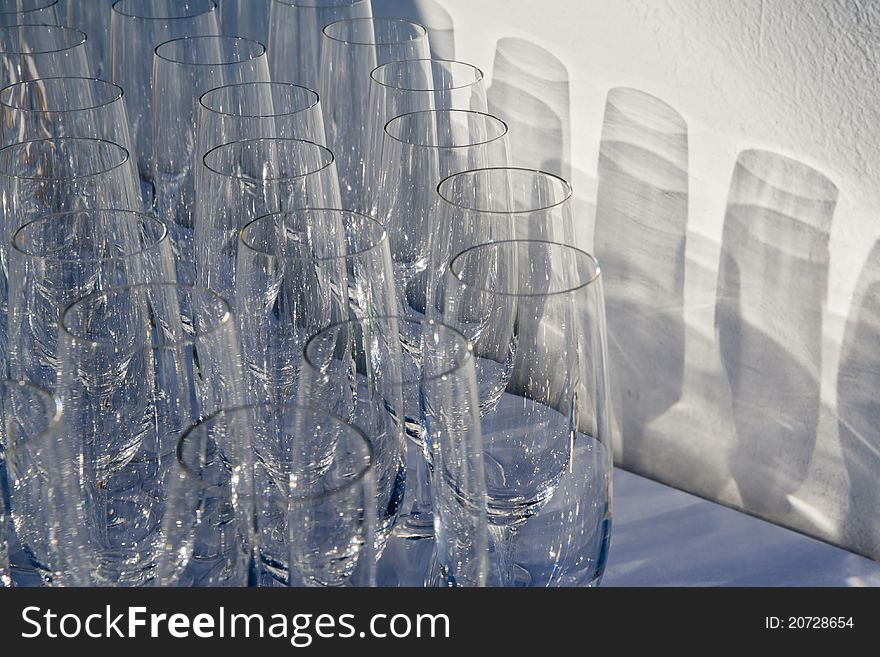 Empty wine glasses organized in rows trowing shadows on the wall. Empty wine glasses organized in rows trowing shadows on the wall.