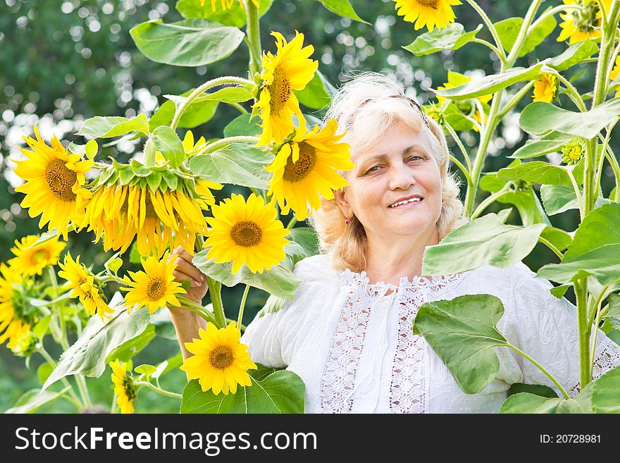 Happy Woman With Sunflowers In Her Garden