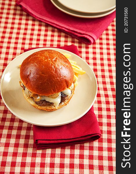 Thick rare cheeseburger with swiss cheese and caramelized onions served with french fries