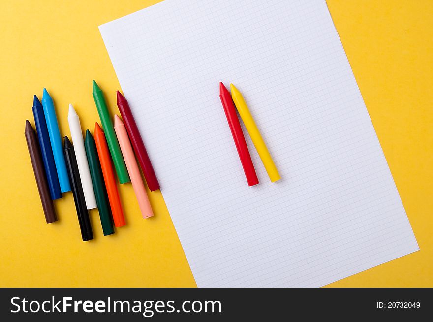 Drawing paper and crayons colored yellow background