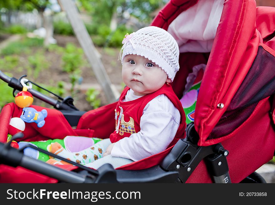 Little pretty girl in a red stroller. Little pretty girl in a red stroller
