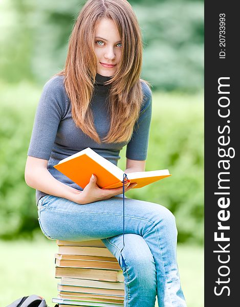 Happy student girl sitting on pile of books