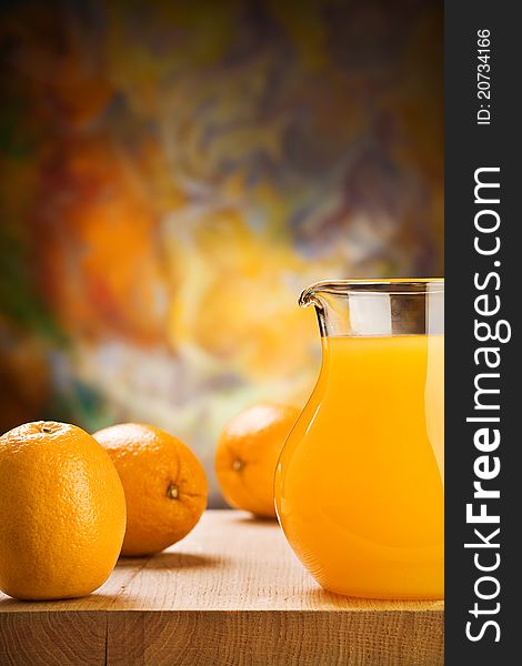 Orange juice in glass jug and oranges on wooden boards. Orange juice in glass jug and oranges on wooden boards