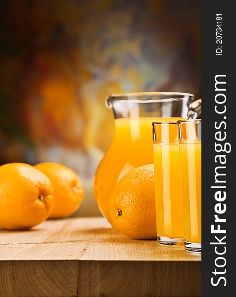 Oranges and juice of oranges on glass and jug on wooden boards