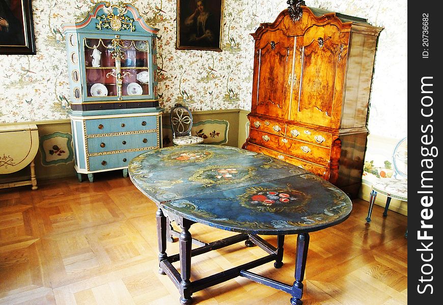 Vintage dining room: an old table, wardrobe, commode and retro wallpaper on walls