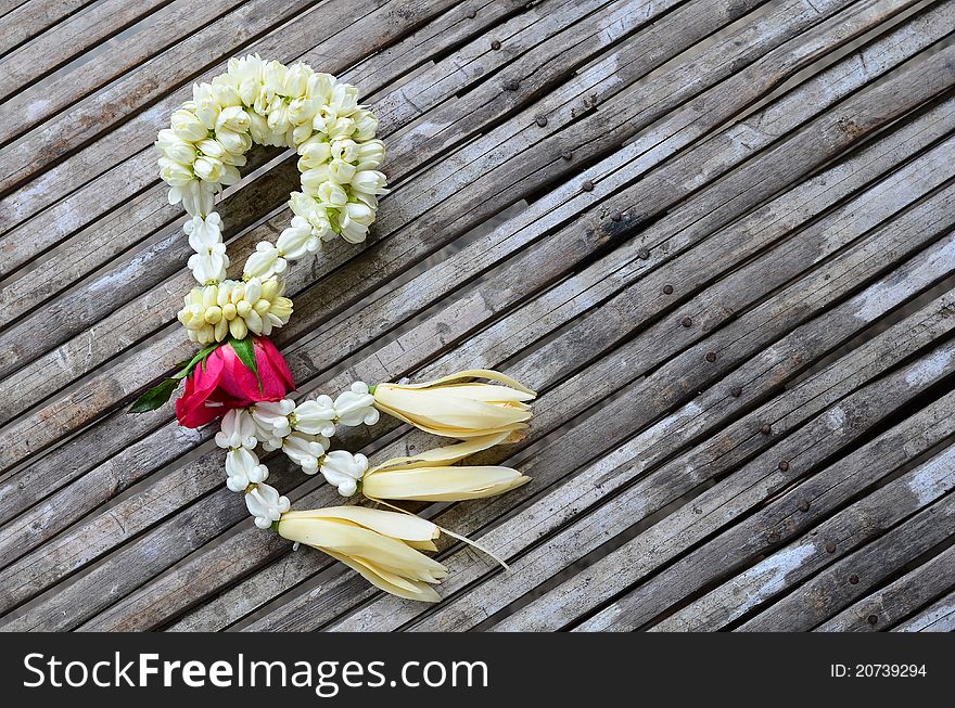 Flowers garland (jasmine, rose, White Champaka and crown flower) on bamboo table