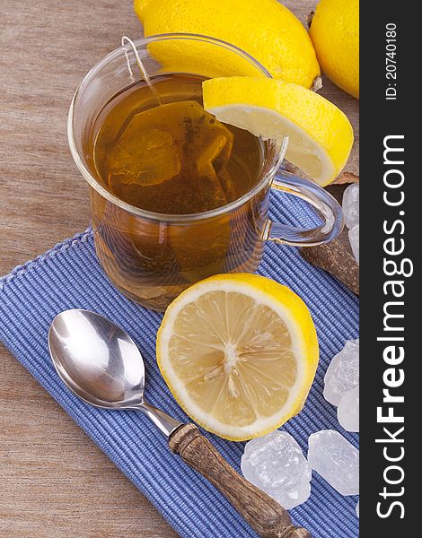 Studio-shot of a glass with fresh hot lemon tea, a slice of lemon, rock sugar and a cinnamon stick.