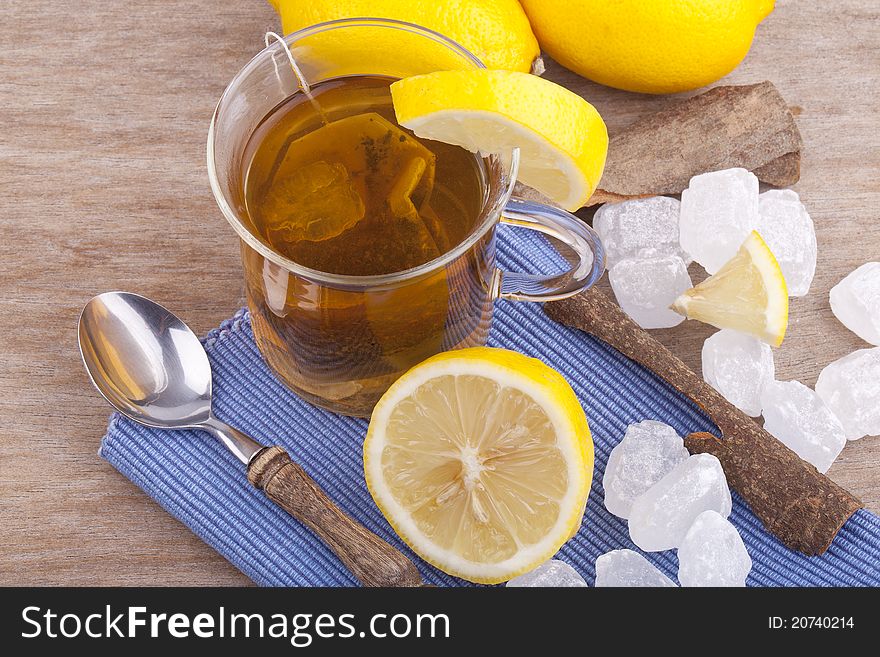 Studio-shot of a glass with fresh hot lemon tea, a slice of lemon, rock sugar and a cinnamon stick.