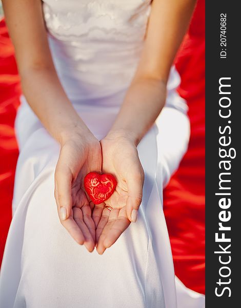 Newlywed woman holding in her hands red heart - symbol of love. Newlywed woman holding in her hands red heart - symbol of love