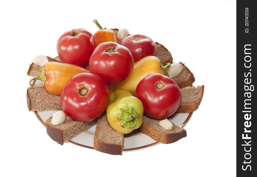 Tomatoes, bread, pepper, garlic lay on a plate. Tomatoes, bread, pepper, garlic lay on a plate