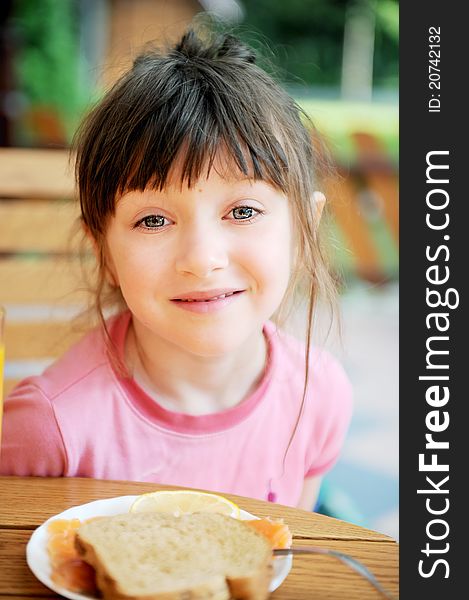 Cute child girl with tumbled hair has breakfast outdoors. Cute child girl with tumbled hair has breakfast outdoors