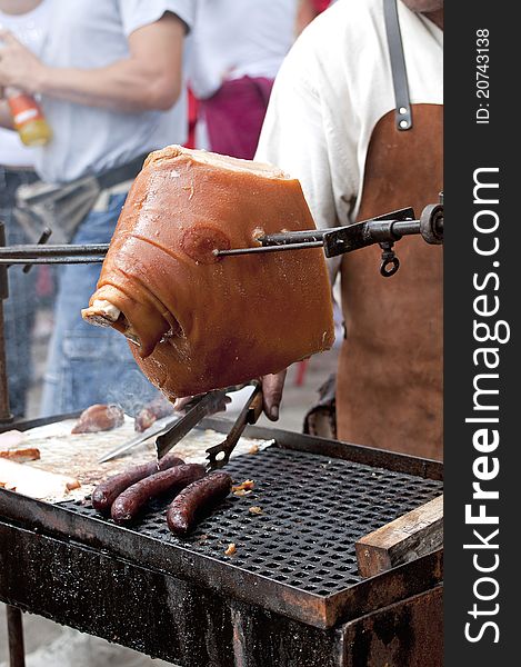 A man is barbecuing piece of pork meat and sausages. A man is barbecuing piece of pork meat and sausages.