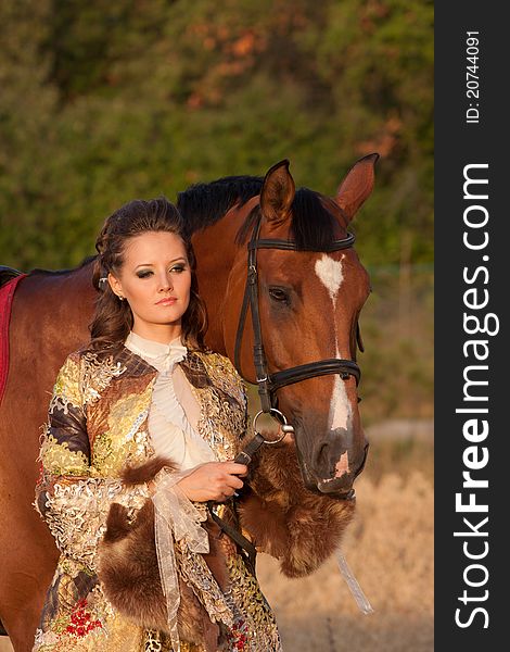 The young pretty woman in clothes of 18 centuries with horse outdoors. The young pretty woman in clothes of 18 centuries with horse outdoors