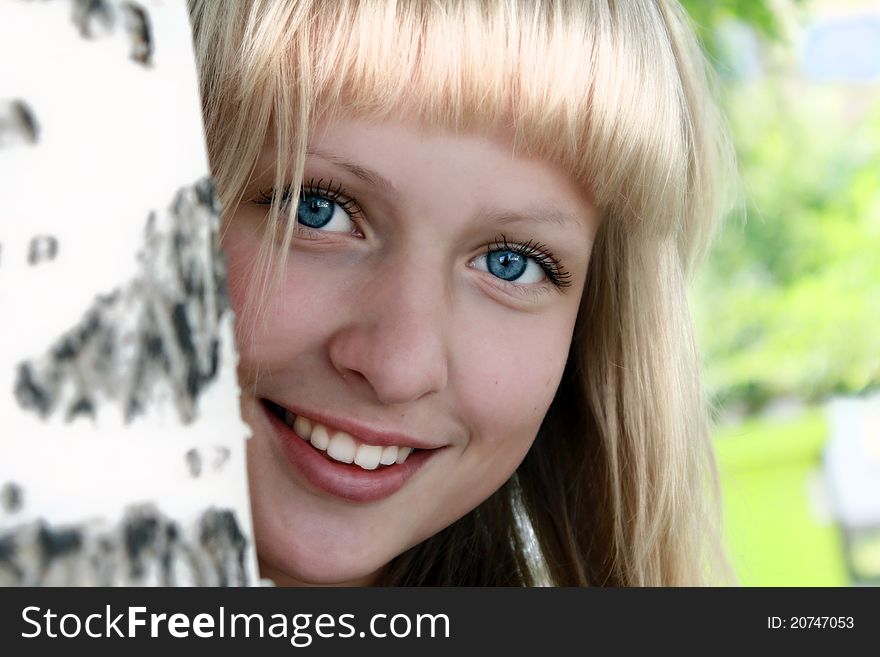 A beautiful girl is smiling near birch. A beautiful girl is smiling near birch