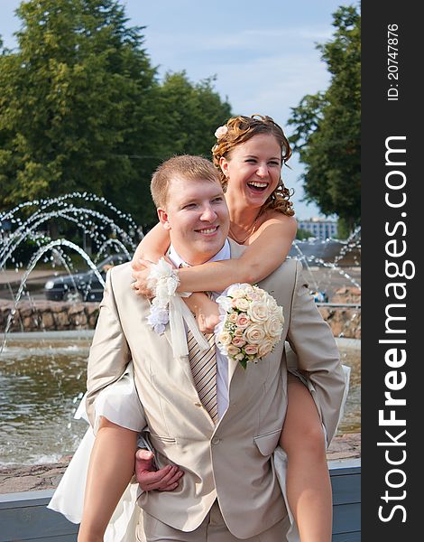 The bride sits on a back at the cheerful groom and laughs. The bride sits on a back at the cheerful groom and laughs