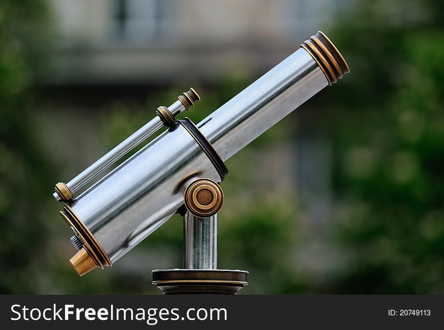 An tourist type telescope against the green trees. An tourist type telescope against the green trees