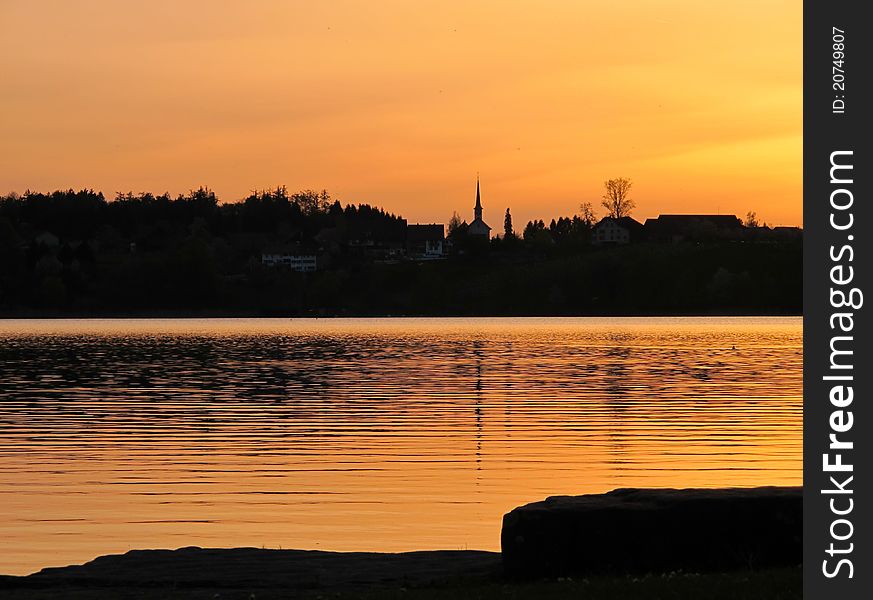 Sunset over the lake. Church and little village.