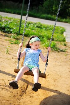 Happy Child Girl Is Swinging In The Playground Royalty Free Stock Photo