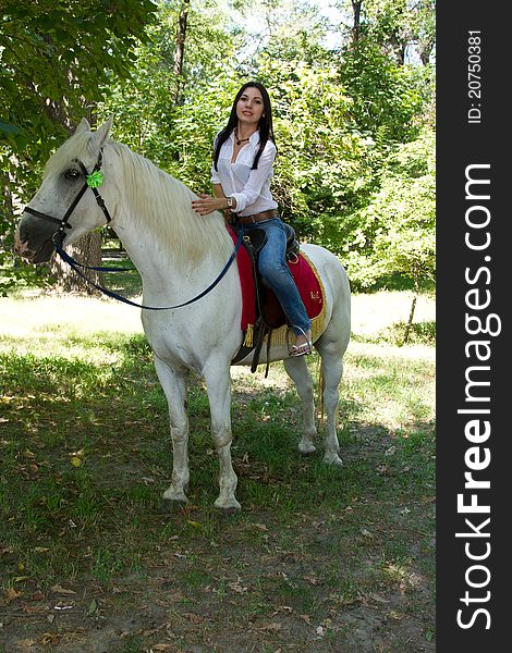 Cute girl in jeans on a horse for a walk in nature. Cute girl in jeans on a horse for a walk in nature