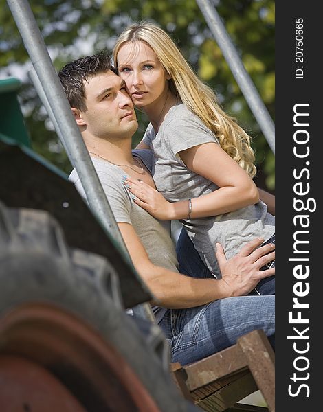 Young couple sitting on tractor in countryside. Young couple sitting on tractor in countryside