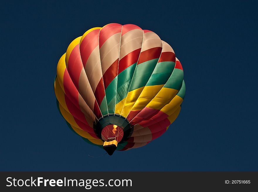 Image of a very colorful hot air balloon buring the burner, passing overhead. Image of a very colorful hot air balloon buring the burner, passing overhead